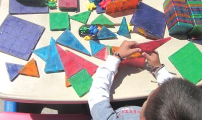 Child stacking brightly colored shapes