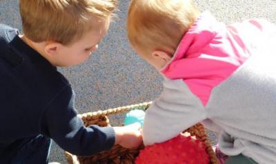 Two children look through a basket of balls.