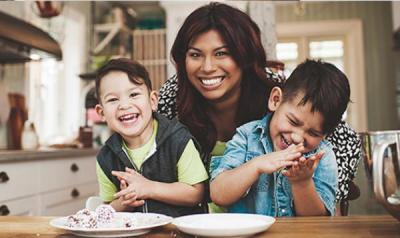 Mother and two sons sitting at the kitchen table and laughing