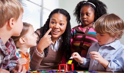 A teacher with kindergartners leading play time 