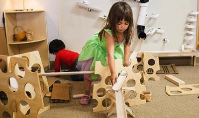 young girl putting together a 3D block puzzles using blocks