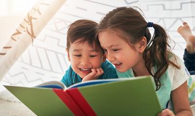 A girl and boy reading a book together