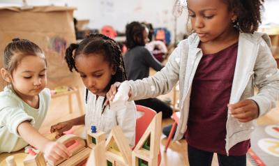 A classroom of children playing with wooden blocks 