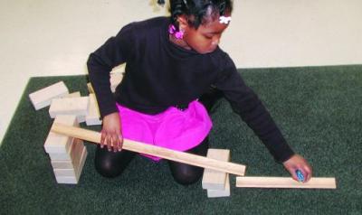 A young girl plays with blocks to make a ramp