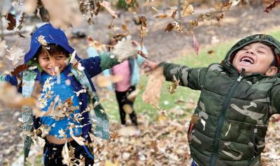 children playing together in fall leaves