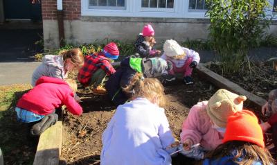 A group of young children leaning in a school garden