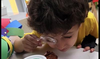 A student using a magnifying glass for a project at school