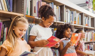 Three children reading books in a library
