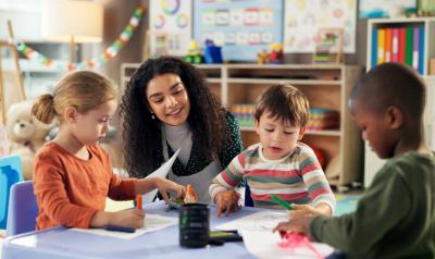 An early childhood educator working with students in a classroom