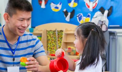 Child and teacher playing with toys in classroom