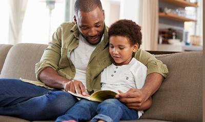 Dad and son reading a book on the couch