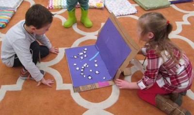Two children creating a project with cardboard box