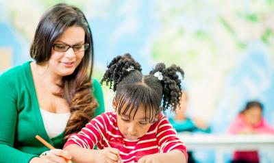 a teacher writing with a child at a table