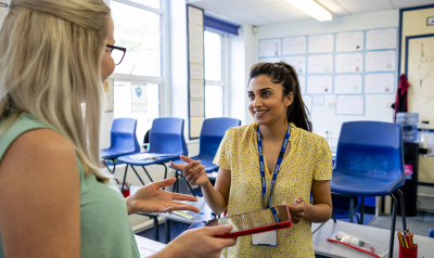 two teachers discussing something with an ipad