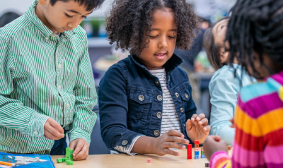 children at a table tinkering with toys