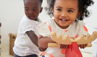 Two children playing on wooden horse