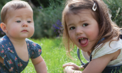 A baby and toddler playing outdoors