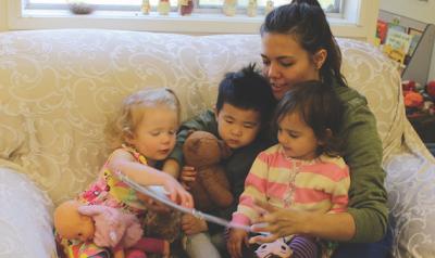 Teacher reading a children's book to three toddlers