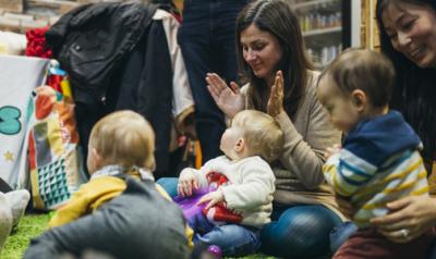 Infants and their parents sit in a circle clapping and singing together