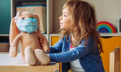 little girl playing with doll and putting a mask on