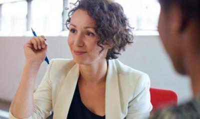 Woman holding pen and listening to someone speak