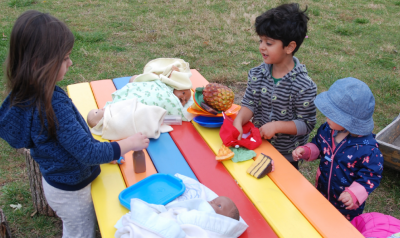 children at an outdoor table with toys