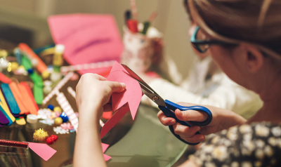 a person cutting a piece of paper around art supplies