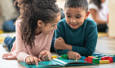 two children on the floor reading together
