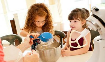 Two young girls baking with a parent