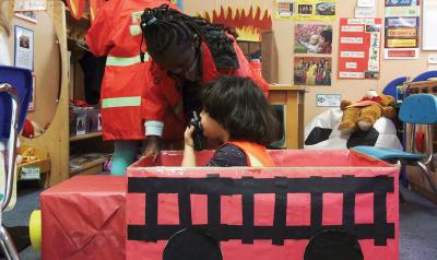 Child pretending to be a firefighter in a cardboard firetruck