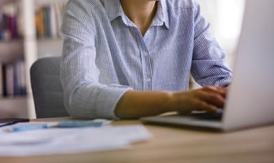 woman sitting at the computer typing on a laptop