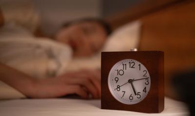 Image of a clock with a woman sleeping in the background