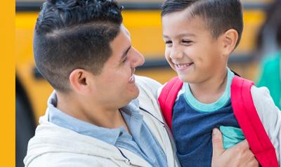 Father and son hugging by the school bus