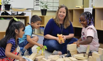 Children and teacher playing in block center in classroom