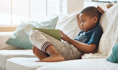 young preschool boy sitting on a couch reading