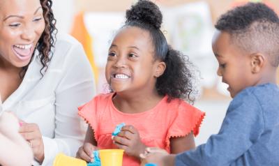 Teacher playing and smiling with two of her preschoolers.