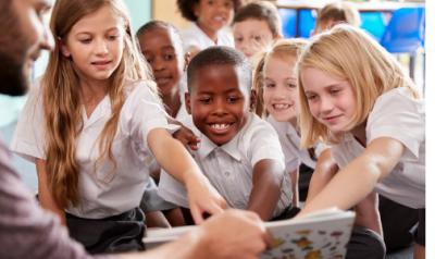 Teacher reading to the class while children point at the book