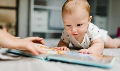 A baby on the floor with a book.