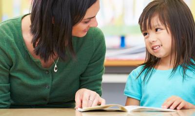 a teacher reading with a child at a table