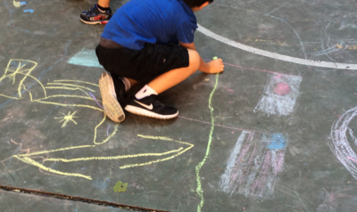 A child drawing with sidewalk chalk.
