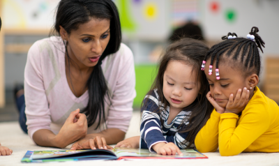 a teacher reading a picture book with children