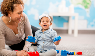 A toddler playing with blocks with a parent.