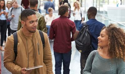 Three young adults walking and talking in a conference setting.