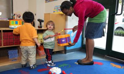 Toddlers in a learning environment playing with female teacher.