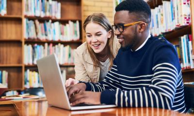 Two young professionals on a computer in the library