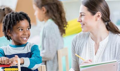 Teacher and preschool boy smiling in a classroom