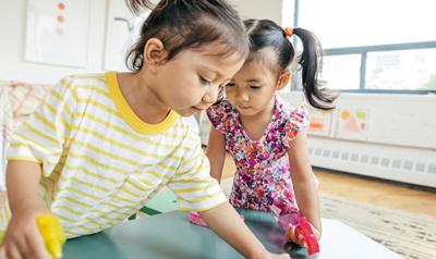 Two preschool girls playing in the classroom