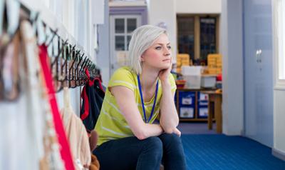 Teacher sitting in a hallway, thinking