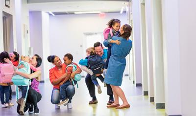 5 parents, each hugging their child in a school hallway