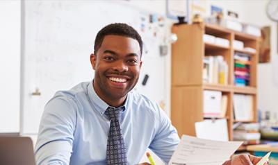 Male teacher in a classroom at a desk